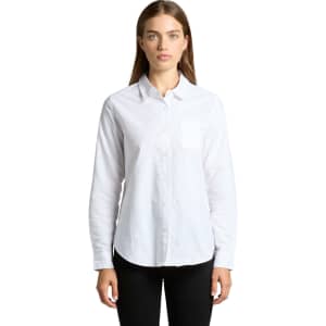 A white button-up shirt featuring long sleeves and a chest pocket. The model poses straight-on against a plain background.