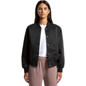 A black varsity bomber jacket with a snap button front, worn by a model. Features a logo on the chest.