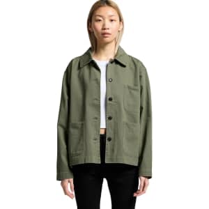 An olive green chore jacket featuring a collared neckline and front pockets, worn by a model.