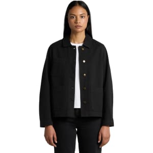 A black canvas chore jacket with button closure and front pockets, modelled by a person wearing a white top.