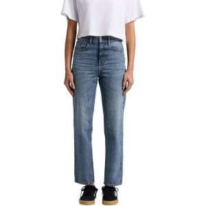 Straight jeans in light blue denim, featuring a high-waisted design. Paired with a white cropped top and black sneakers.