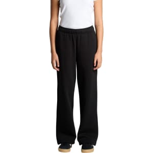 Cuffless track pants in black, featuring a relaxed fit and an elastic waistband. The model stands with hands at sides.