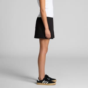 Black track shorts displayed on a model from the side, paired with black sneakers. The shorts feature a logo.