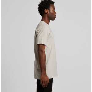 A side view of a beige Staple Tee T-shirt on a model, featuring short sleeves and a simple design.