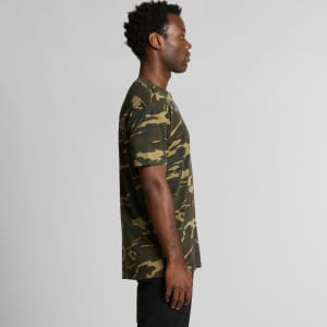 A camo-patterned T-shirt in shades of green and brown, featuring a simple design and a logo on the front.