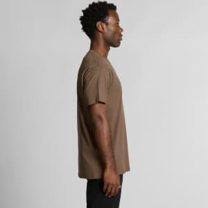 A side view of a man wearing a brown organic T-shirt, featuring short sleeves and a simple design.