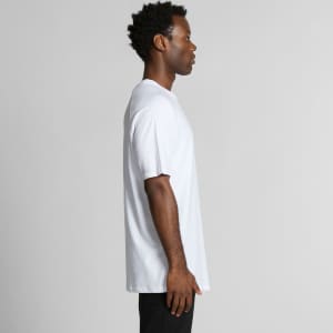 A side view of a man wearing a white Staple Raglan Tee, featuring a relaxed fit and short sleeves.