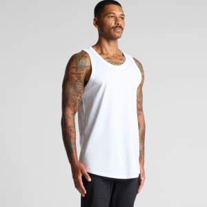 A man wearing a white singlet stands against a plain background. The singlet features a logo.