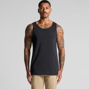 A man stands wearing a plain black singlet, showcasing its simple design and fit. The singlet has a logo.