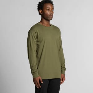 A long sleeve tee in olive green, featuring a simple design and a logo. The model stands against a neutral background.