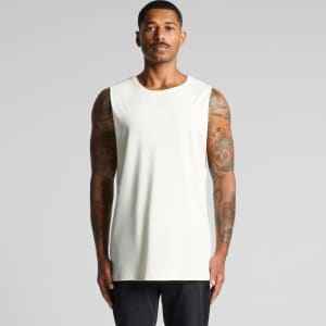 A sleeveless, light-coloured tank top worn by a person with tattoos. The product features a logo.