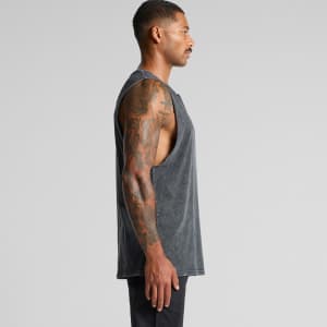A man with tattoos wearing a grey Stone Wash Barnard Tank top, viewed from the side. The tank has a relaxed fit and sleeveless design.