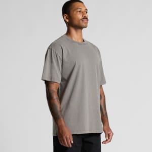 A man wearing a heavy faded grey T-shirt, displaying a relaxed fit and short sleeves. The shirt features a logo.