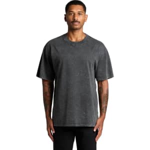 A man wearing a stone wash heavy tee in a dark grey shade. The shirt features a logo on it.