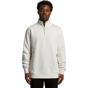 A man wearing a cream-coloured half zip crew jumper. The garment features a stand-up collar and has a logo.