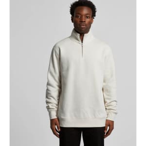 A man is wearing a cream-coloured half zip crew jumper with a relaxed fit, featuring a stand-up collar.