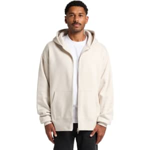 A man wearing a cream heavy zip hoodie with a front pocket and a hood, featuring a logo.