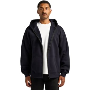 A navy zip-up hoodie is worn by a model, featuring a front zipper and a hood. The hoodie includes a logo.