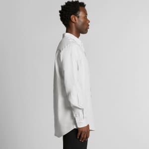A linen button-up shirt in light grey, featuring a side view of a model wearing it. The shirt has a logo.