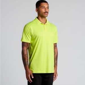 A man wearing a bright yellow polo shirt stands against a light background. The shirt has a logo on it.