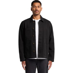 A man wearing a black canvas chore jacket with front pockets, styled over a white t-shirt.