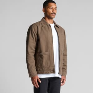 A brown canvas heavy jacket featuring two front pockets and a logo, worn by a model against a neutral backdrop.
