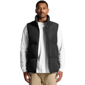 A puffer vest in black, featuring a zip closure and a high collar, worn over a white long-sleeve shirt.