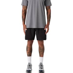 Active Pro Shorts in black, featured on a model wearing a grey shirt and athletic shoes. The model has visible tattoos.
