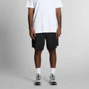 Active Pro Shorts in black, featuring a relaxed fit and an associated logo, worn with a white T-shirt and sports shoes.