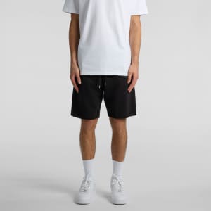 A person wearing black sports shorts styled with a plain white t-shirt and white sneakers.