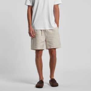 Linen shorts in a light beige colour, featuring an elastic waistband and a casual fit, paired with a white t-shirt.