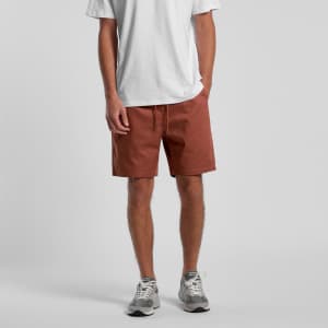 Rust-coloured dress shorts with an elastic waistband and drawstring, styled with a white t-shirt and sneakers.