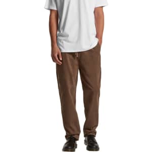 Brown cord pants displayed on a model wearing a white t-shirt and black shoes, with hands in pockets.