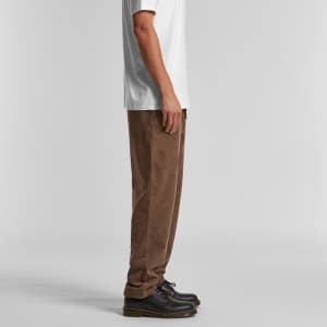 Cord pants in brown, displayed from the side on a model wearing a white T-shirt and black shoes.