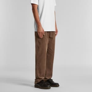 Cord pants in a rich brown colour, featuring a relaxed fit, paired with a white t-shirt and black shoes.