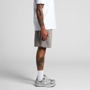 Light grey track shorts with a relaxed fit, seen from the side, paired with a white t-shirt and grey sneakers.