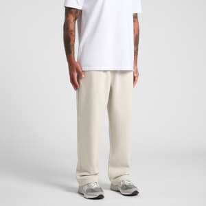 A person wearing cream-coloured cuffless track pants and a white t-shirt, standing with hands at their sides.