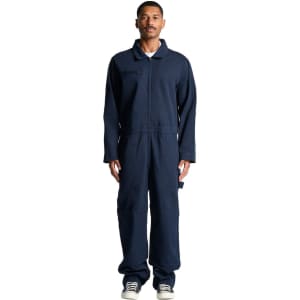 A male model wearing navy blue canvas coveralls, featuring a collar and long sleeves. The outfit has a logo.