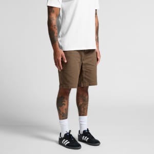 Canvas shorts in a brown shade, featuring a relaxed fit and cargo-style pockets, paired with a plain white T-shirt and black sneakers.