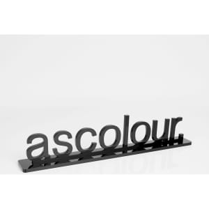 A black promotional display with the word "ascolour" in stylish lettering, reflecting on a smooth surface.