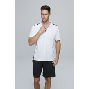 A man wearing a white polo shirt with black accents, paired with black shorts, posing against a grey background.