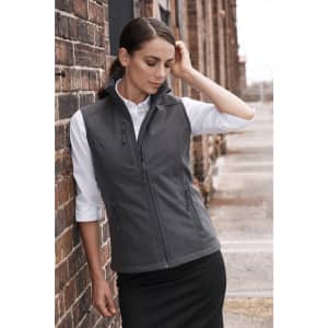 A grey vest with a fitted design worn over a white shirt, showcased against a brick wall backdrop.