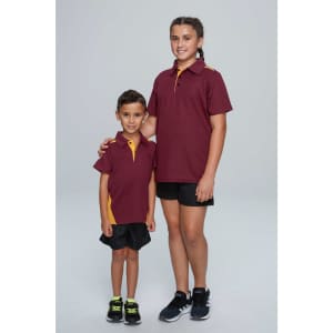 Two children wearing maroon polo shirts with yellow accents, standing side by side against a neutral background.