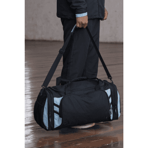 A black and light blue duffle bag being held by a person, featuring multiple zippers and a shoulder strap.