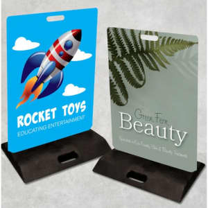 Two footpath signs: one blue with a rocket design and the other green featuring ferns, both on black bases.