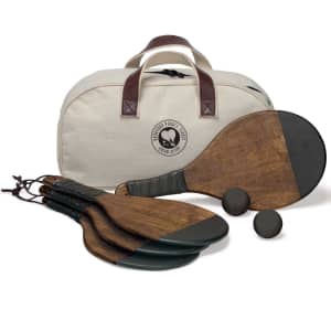 A paddle tennis set featuring four wooden paddles, two black balls, and a cream bag with a logo.