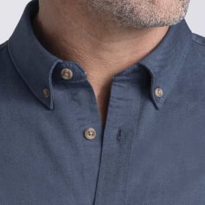 Men's button-up shirt in a dark blue colour with a collar and button details. Features a logo on the fabric.