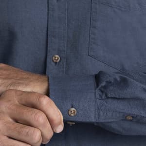 A men's button-up shirt in dark blue with a chest pocket and buttoned cuffs. Features a subtle branding logo.