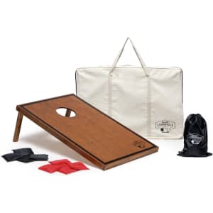 A wooden cornhole board with an oval hole, accompanied by black and red bags and a carry bag featuring a logo.