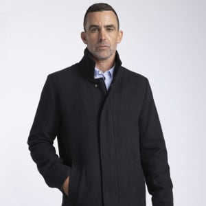 A wool jacket in black, featuring a collar and front pockets, worn by a male model with short hair.
